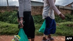 FILE - Sex workers walk home after receiving aid during a lockdown to fight COVID-19 in Kampala, Uganda, May 7, 2020. A bill passed in the first week of May 2021 would enshrine criminalization of same-sex relations, sex work and those living with HIV. 