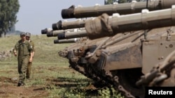 Israeli soldiers walk near tanks close to the ceasefire line between Israel and Syria on the Israeli occupied Golan Heights, May 6, 2013.