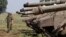 Israeli soldiersjavascript:WebForm_DoPostBackWithOptions(new%20WebForm_PostBackOptions("ctl00$ctl00$ctl00$cphContent$cphContent$cphToolbarUp$tbiSave",%20"",%20true,%20"art",%20"",%20false,%20true)) walk near tanks close to the ceasefire line between Israel and Syria on the Israeli occupied Golan Heights, May 6, 2013.