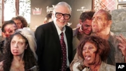 FILE - Legendary horror picture film director George A. Romero poses on the red carpet with zombie's just before the premiere of his latest motion picture, "Land of The Dead," during Cine Vegas, June 18, 2005, at the Palms Hotel and Casino in Las Vegas.
