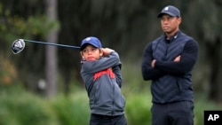 FILE - Tiger Woods, right, watches as his son Charlie tees off during a practice round of the Father-Son Challenge golf tournament, Dec. 17, 2020, in Orlando, Fla. (AP Photo/Phelan M. Ebenhack)