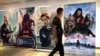 FILE - A man wearing a face mask walks past a poster for the Disney movie "Mulan" at a movie theater in Beijing, on Sept. 11, 2020. 