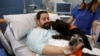 โจเอล บัวเอโน ผู้ป่วย ICU ในโรงพยาบาล Hospital del Mar ในเมืองบาร์เซโลนา ประเทศสเปน ขณะเล่นกับสุนัขบำบัดที่โรงพยาบาลและมูลนิธิ Affinity นำเข้ามาเมื่อ 18 เมษายน 2024 (ที่มา: Reuters)