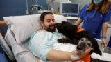 โจเอล บัวเอโน ผู้ป่วย ICU ในโรงพยาบาล Hospital del Mar ในเมืองบาร์เซโลนา ประเทศสเปน ขณะเล่นกับสุนัขบำบัดที่โรงพยาบาลและมูลนิธิ Affinity นำเข้ามาเมื่อ 18 เมษายน 2024 (ที่มา: Reuters)
