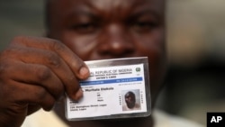 File- Muritala Diekola, displays his voters registration card in Lagos, Nigeria.