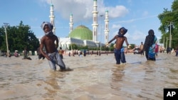 People walk through floodwaters following a dam collapse in Maiduguri, Nigeria, Sept. 10, 2024.