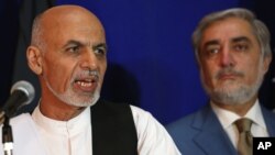 FILE - Afghan presidential candidate Ashraf Ghani Ahmadzai, left, speaks as another candidate Abdullah Abdullah listens during a joint press conference in Kabul, Afghanistan, Aug. 8, 2014. 