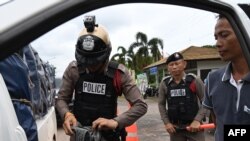 This photo taken May 24, 2019 shows a Thai policeman inspecting the belongings of a driver at a road checkpoint in Muang, Nakhon Phanom province near the Laos border crossing. 