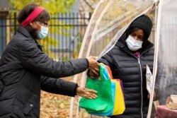 FILE - Sister Jenthia Abell hands out COVID-19 survival kits to community members during a training session as part of an outreach program to the Black community to increase vaccine trial participation in Rochester, New York, Nov. 14, 2020.
