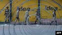 Indian paramilitary and police patrol near a barbed wire fence during a curfew imposed on the Kashmiri summer capital in Srinagar on July 19, 2013.