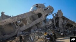 Satu keluarga mengendarai gerobak yang ditarik kuda melewati masjid yang hancur di Beit Lahia, utara Jalur Gaza, 29 Januari 2025. (Foto: Jehad Alshrafi/AP Photo)