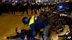 A Dutch riot policeman tries to get his dog to let go of a man after riots broke out during a pro-Erdogan demonstration at the Turkish consulate in Rotterdam, Netherlands, March 12, 2017. 