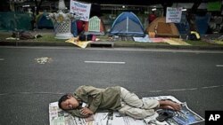 A supporter of the People's Alliance for Democracy, also known as the Yellow Shirts, sleeps on the street near Government House in Bangkok, Thailand, January 27, 2011.