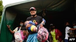 Los migrantes hondureños que regresan voluntariamente a Honduras se bajan de un camión del ejército en El Florido, Chiquimula, Guatemala el 19 de enero de 2021.