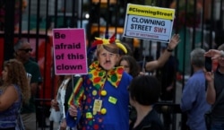 A man dressed as a clown and wearing a Boris Johnson mask protest in front of the Downing Street gate in London, Aug. 29, 2019.