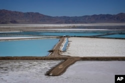 A truck is parked between brine evaporation ponds at Albemarle Corp.'s Silver Peak lithium facility, Oct. 6, 2022, in Silver Peak, Nev. (AP Photo/John Locher, File)