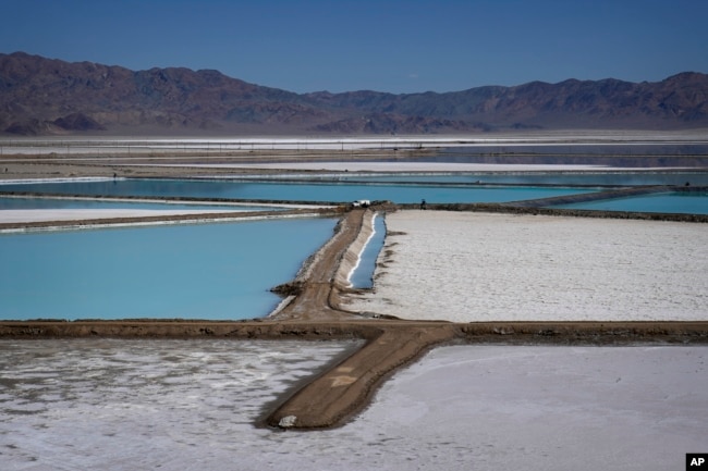 A truck is parked between brine evaporation ponds at Albemarle Corp.'s Silver Peak lithium facility, Oct. 6, 2022, in Silver Peak, Nev. (AP Photo/John Locher, File)