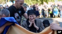 A mother cries near the coffin of her son killed by a Russian rocket attack at a Ukrainian military academy, during his funeral ceremony in Poltava, Ukraine, Sept. 7, 2024. 