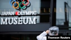 A policeman holds onto his hat because of strong wind gusts caused by a tropical storm Nepartak in front of the Japan Olympic Museum in Tokyo, July 27, 2021.