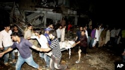 ພວກຜູ້ຊາຍພາກັນຫາມ ເອົາຄົນທີ່ໄດ້ຮັບບາດເຈັບ ອອກຈາກ ບ່ອນເກີດເຫດວາງລະເບີດ ທີ່ນະຄອນກາຣາຈີ, ປາກິສຖານ, ວັນທີ 3 ມີນາ 2013..