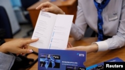 Employees demonstrate a payment card during a tour at a branch of VTB bank in Moscow, Russia, May 30, 2019.