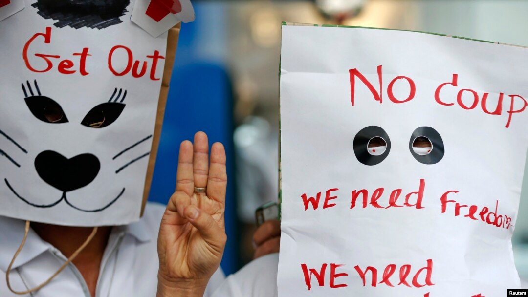 Para demonstran anti-kudeta mengenakan topeng bertuliskan pesan sambil mengacungkan salam 'tiga jari' dalam aksi unjuk rasa di sebuah pusat perbelanjaan di Bangkok (1/6).