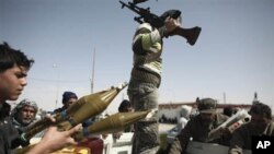 Defected Libyan soldiers and volunteers load weapons onto a truck on the outskirts of the eastern town of Brega, Libya, Thursday, March 3, 2011. Mutinous army units in pickup trucks armed with machine-guns and rocket launchers deployed around the strategi