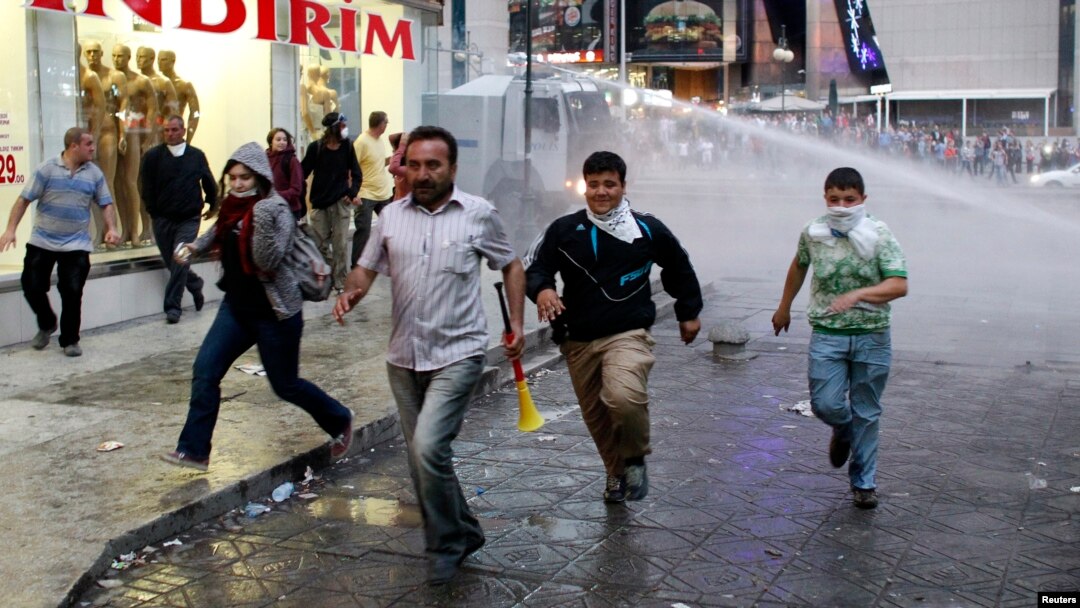 Demonstran anti-pemerintah di Ankara berlari melindungi diri dari semburan meriam air dan gas air mata seiring upaya polisi membubarkan mereka (5/6). (Reuters/Umit Bektas)