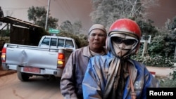 Warga dengan wajah kotor karena abu mengendarai sepeda motor di tengah muntahan abu dari Gunung Sinabung, di desa Sukandebi di Kabupaten Karo, Sumatra Utara (13/6). (Reuters/Antara/Rony Muharman)