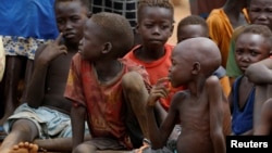 Anak-anak yatim piatu dan yang terpisah dari orang tua mereka di Kadugli berkumpul untuk makan daun rebus di Kamp Pengungsi di wilayah yang dikuasai Gerakan Pembebasan Rakyat Sudan-Utara (SPLM-N) di Pegunungan Nuba, Kordofan Selatan, Sudan, 22 Juni 2024. (Thomas Mukoya/REUTERS)