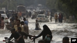 Pakistanis wade through a flooded road caused by heavy monsoon rainfall in Karachi, Pakistan on Saturday, Sept. 10, 2011.