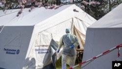 FILE - An employee of the Klinikum Bremen-Ost walks in protective clothing near, where coronavirus tests are being administered, in Bremen, Germany, March 16, 2020.