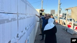 People check candidates lists during parliamentary elections of Iraq’s semi-autonomous northern Kurdish region, in Irbil, Oct. 20, 2024.