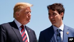 FILE - In this June 8, 2018, file photo, President Donald Trump talks with Canadian Prime Minister Justin Trudeau during a G-7 Summit welcome ceremony in Charlevoix, Canada. 