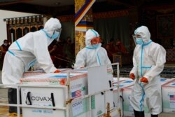 This photograph provided by UNICEF shows airport personnel in protective suit handle unloaded 500,000 doses of Moderna COVID-19 vaccine gifted from the United States arrived at Paro International Airport in Bhutan, July 12, 2021.