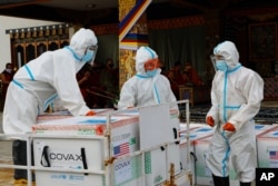 This photograph provided by UNICEF shows airport personnel in protective suit handle unloaded 500,000 doses of Moderna COVID-19 vaccine gifted from the United States arrived at Paro International Airport in Bhutan, July 12, 2021.