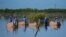 Women wade through a swamp to plant mangrove seedlings, near Progreso, Mexico, Oct. 6, 2021.