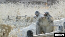 People get wet from sea spray caused by huge waves as a cold front moves over Cape Town, South Africa.