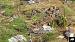 Family members survey their home, which was destroyed in the passing of Hurricane Beryl, in Ottley Hall, St. Vincent and the Grenadines, on July 2, 2024.