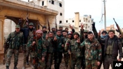 In this photo released Feb. 16, 2020 by the Syrian official news agency SANA, Syrian army soldiers flash the victory sign in the Rashideen neighborhood, in Aleppo province, Syria. 