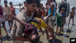 A man shakes a Rohingya Muslim boy while trying to revive him after the boat he was traveling in capsized just before reaching shore at Shah Porir Dwip, Bangladesh, Thursday, Sept. 14, 2017. Nearly three weeks into a mass exodus of Rohingya fleeing violence in Myanmar, thousands were still flooding across the border Thursday in search of help and safety in teeming refugee settlements in Bangladesh. 