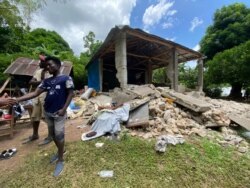 A man stands in the front yard of his home, which was completely destroyed by the 7.2 magnitude earthquake in Maniche, Haiti, Aug. 19, 2021. (Jean Handy Tibert/VOA)