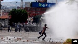 Un estudiante lanza piedras a la policía antimotines que intenta disolver una manifestación de protesta contra los resultados de las elecciones presidenciales.