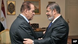Caretaker Prime Minister Kamal el-Ganzouri, left, shakes hands with newly elected President Mohamed Morsi in Cairo, June 25, 2012. (photo released by Middle East News Agency)