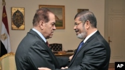 PM sementara Mesir, Kamal el-Ganzouri (kiri) memberikan selamat kepada Presiden terpilih Mohamed Morsi di Kairo, Senin (25/6).