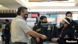 Senator Texas Ted Cruz (kanan) berbicara kepada seorang penjaga keamanan di pemeriksaan bandara di Bandara Internasional Cancun sebelum menaiki pesawat kembali ke AS, di Cancun, Meksiko, Kamis, 18 Februari 2021. (Foto: Reuters)