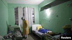 A caregiver checks elderly man at the Sao Francisco de Assis shelter for the elderly, where nine residents with symptoms of the coronavirus disease have been placed in isolation, according to the shelter, in Sao Joao do Meriti, Brazil, June 12, 2020. 