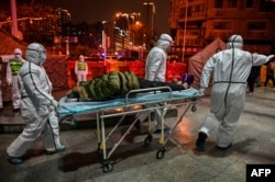 FILE - Medical staff members wearing protective clothing to help stop the spread of a deadly virus which began in the city, arrive with a patient at the Wuhan Red Cross Hospital in Wuhan, China, Jan. 25, 2020.