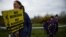 FILE - A woman carries signs as children hold an EU flag as they attend a protest against Brexit on the border crossing between the Republic of Ireland and Northern Ireland in Carrickcarnon, Ireland, March 30, 2019.