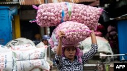 Seorang perempuan membawa bawang putih di sebuah pasar di Surabaya, 22 Desember 2016. (Foto: Juni Kriswanto/AFP)